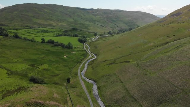 A long travelling aerial shot of the Barbon Beck Valley, Carnforth, Lancashire showing the stunning and undulating landscape.
