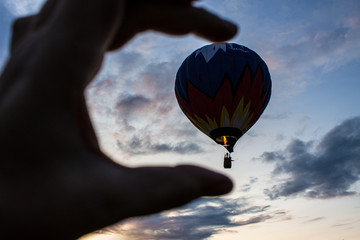 flying balloon with passengers in a basket against the blue sky at the festival of Aeronautics in...
