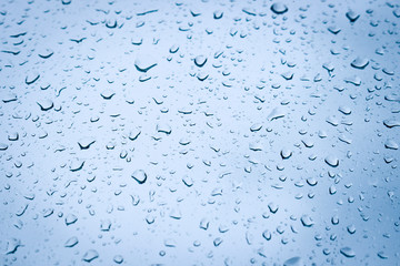 Large drops of water on the glass. Raindrops on the windshield of a car against the background of the sky sky.