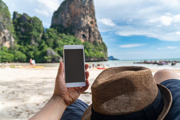 Young man traveler using  smartphone at tropical sand beach, Summer vacation concept