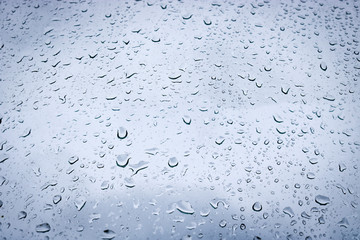 Large drops of water on the glass. Raindrops on the windshield of a car against the background of the sky sky.