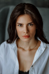 Fototapeta premium Vertical close-up portrait of beautiful young brunette woman. Looking at the camera, on a dark background