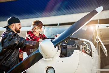 young father in black leather jacket and his son in aviator glasses check engine and turbine of...