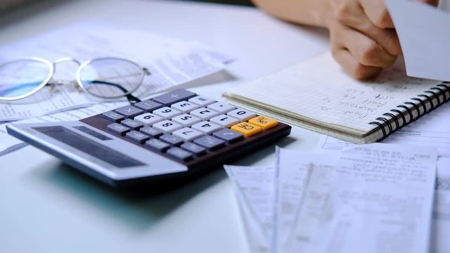 Stressed young woman checking bills, taxes, bank account balance and calculating expenses in the living room at home