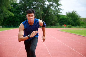 Young Asian Athletic man running in track to practice himself and listen to music