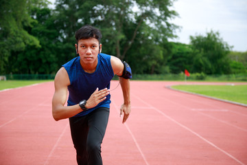 Obraz premium Young Asian Athletic man running in track to practice himself and listen to music