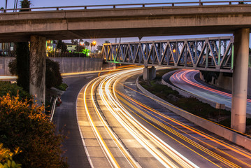 Streaking headlights and tail lights of the flowing traffic of the 101 freeway as it passes under bridges in Ventura.