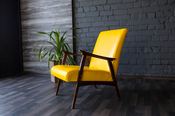 Stylish retro yellow chair in the gray room. Brick gray wall. Room.