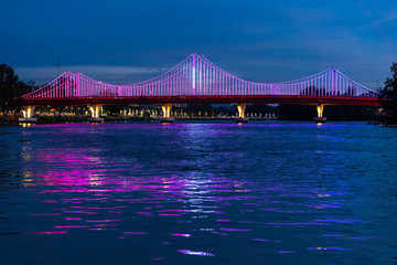 Fototapeta premium The city lights of Surat Thani at twilight with the Bridge and reflection over the Tapee River in Surat Thani , Thailand
