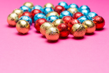 Chocolates in a multi-colored foil on a pink background