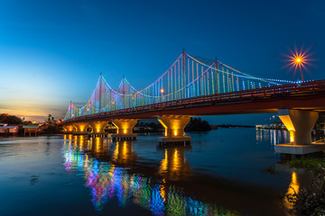 The city lights of Surat Thani at twilight with the Bridge and reflection over the Tapee River in Surat Thani , Thailand