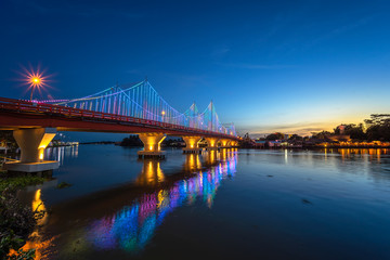 The city lights of Surat Thani at twilight with the Bridge and reflection over the Tapee River in Surat Thani , Thailand