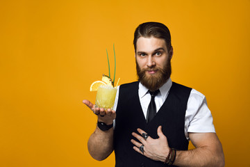 bearded barman with beard holding cocktail in waistcoat - obrazy, fototapety, plakaty