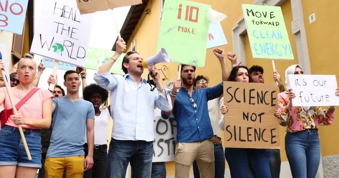 Public demonstration on the street against global warming and pollution. Group of multiethnic people making protest about climate change and plastic problems in the oceans