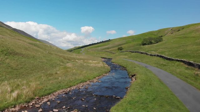 Ascending shot of the Barbon Beck Valley, Carnforth, Lancashire. This stunning countryside features a stream running alongside a small country lane.