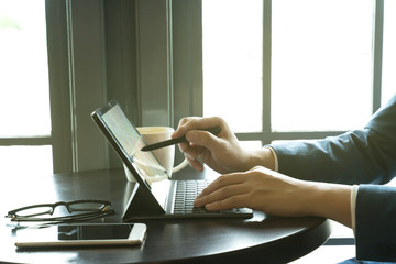 businessman point the stylus pen to tablet for analysis graph visualization at coffee shop