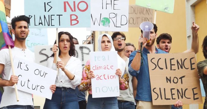 Public demonstration on the street against global warming and pollution. Group of multiethnic people making protest about climate change and plastic problems in the oceans