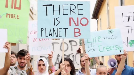 Public demonstration on the street against global warming and pollution. Group of multiethnic people making protest about climate change and plastic problems in the oceans