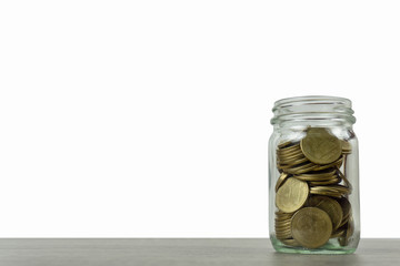 Savings and investment concepts. Stack of coins in a glass jar on wooden table isolated on white background and space.
