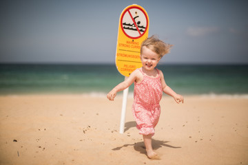 Little girl on the beach, island  Fuerteventura, Corralejo, sign  of a strong wind, swimming is prohibited