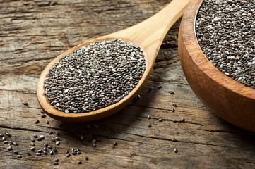 Chia seeds ( Salvia Hispanica ) in wooden spoon and bowl on wooden rustic background. Cereal healthy food contains omega 3, a dietary supplement gluten free