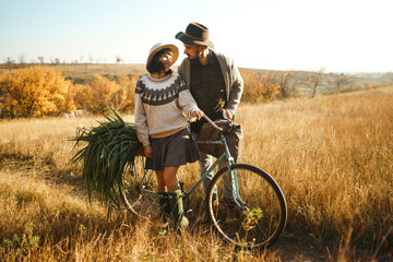 Lovely hipster couple with bike . Couple wearing beautiful hats and sweaters. Lifestyle, happy couple of two play on a sunny day in the park. The concept of youth, love and lifestyle. Sunset in autumn