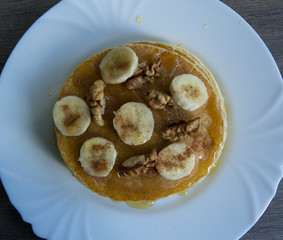 Pancakes with bananas, honey and walnuts on a plate