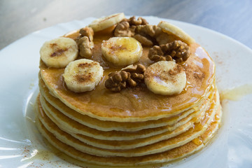 Pancakes with bananas, honey and walnuts on a plate