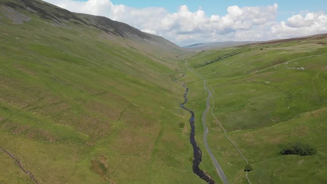 Descending into the Barbon Beck Valley, Carnforth, Lancashire, England. This stunning countryside features a stream running alongside a small country lane.