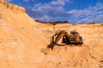 Sand mining concept. Old quarry sand excavator with heavy machinery. Construction industry. Old rusty bulldozer machine at break.