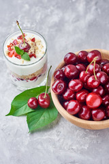 Cherry granola or smoothie in glass and fresh berries in a wooden bowl. Healthy breakfast