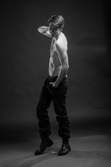 Full length portrait of a sexy young man in jeans and shirtless posing at studio.