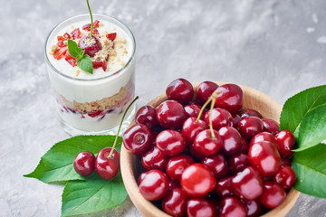 Cherry granola or smoothie in glass and fresh berries in a wooden bowl. Healthy breakfast