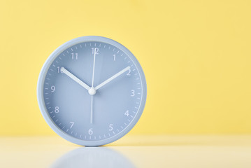 Gray classic alarm clock on a pastel yellow background with copy space