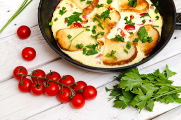 Rustic omelette breakfast with tomatoes and parsley on white rustical background
