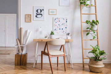 Design scandinavian interior of home office space with stylish chair, wooden desk, ladder, cube, elegant accessories and mock up posters frames. Stylish home decor. Template. White wall. 