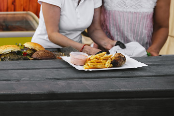 Chef making beef burgers outdoor on open kitchen food festival event. Street food ready to eat on a food stall.