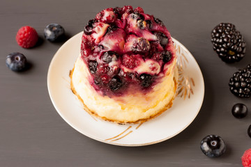 Delicious cottage cheese casserole with berries, cottage cheese pudding with berries. Appetizing fresh cottage cheese casserole with blueberries, currant  and blackberries on a gray background.