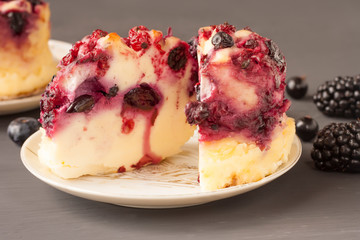Delicious cottage cheese casserole with berries, cottage cheese pudding with berries. Appetizing cottage cheese casserole with blueberries, raspberries  and blackberries on a dark gray background.
