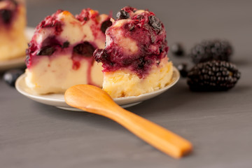Delicious cottage cheese casserole with berries, cottage cheese pudding with berries. Appetizing fresh cottage cheese casserole with blueberries, currant  and blackberries on a dark gray background.