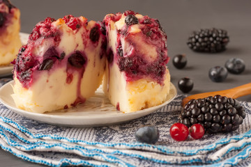 Tasty cottage cheese casserole with berries, cottage cheese pudding with berries. Appetizing fresh cottage cheese casserole with blueberries, black currant, raspberries and blackberries on a napkin 
