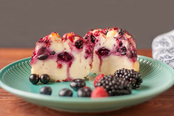 Delicious cottage cheese casserole with berries, cottage cheese pudding with berries. Appetizing fresh cottage cheese casserole with blueberries, raspberries, black currant and blackberries on a table