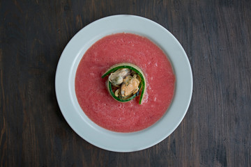 Traditional spanish cold gazpacho soup with mussels. Wooden background.