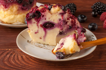 Delicious cottage cheese casserole with berries, cottage cheese pudding with berries. Appetizing fresh cottage cheese casserole with blueberries, raspberries and blackberries on a table