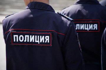 Obraz premium Russian police officers during a patrol on a city street. View from the back