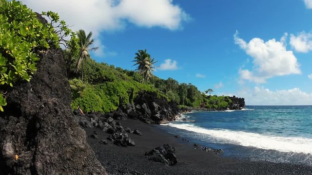 An early morning view of the hidden black sand beach at Waianapanapa State Park, a popular destination among tourists.