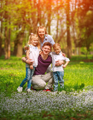 Portrait of family having fun in flowering city park on bright sunny day happily spending their leisure time together outdoors