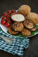 Cutlets from minced meat with paprika, tomatoes and herbs in a bowl on a white dish with a sauce. Wooden background.