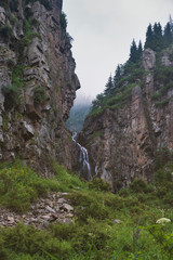 Waterfall between the rocks in the foggy mountains. Kazakhstan, Almaty, gorge Butakovskoe