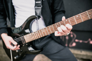 Obraz na płótnie Canvas Man with a black electric guitar outdoors - blues rock music